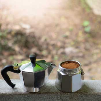 Moka pot and ground coffee - garden background