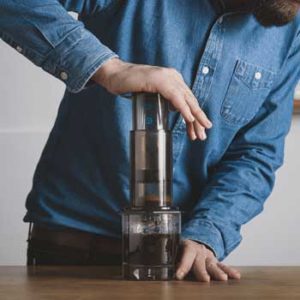 Pressing down on the plunger of the AeroPress coffee maker